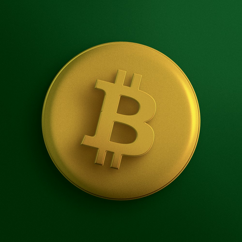 a yellow bit coin sitting on top of a green surface