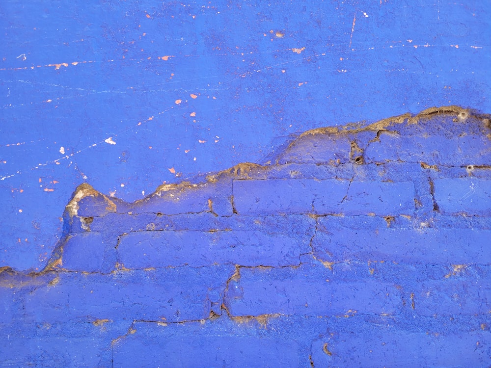 a red fire hydrant sitting on the side of a blue brick wall