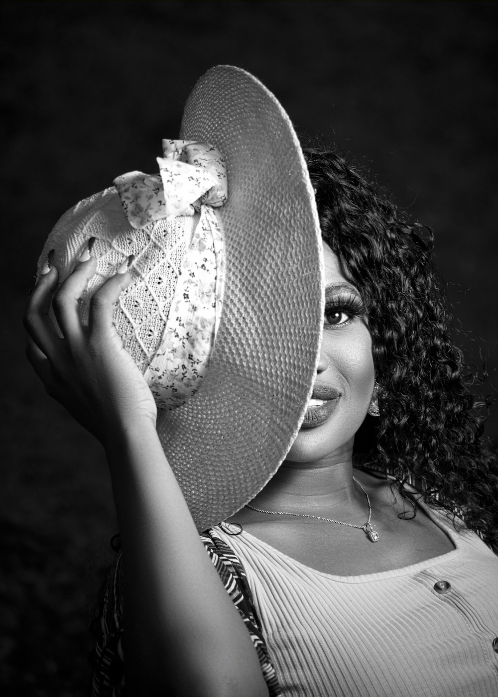 a woman wearing a large hat holding a piece of cake