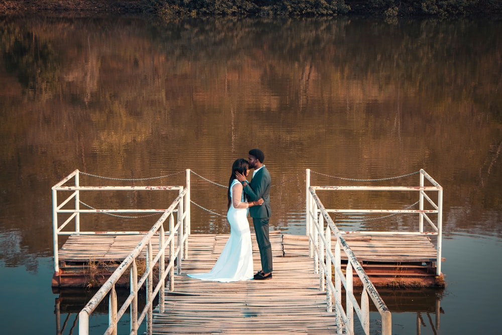 a bride and groom standing on a dock