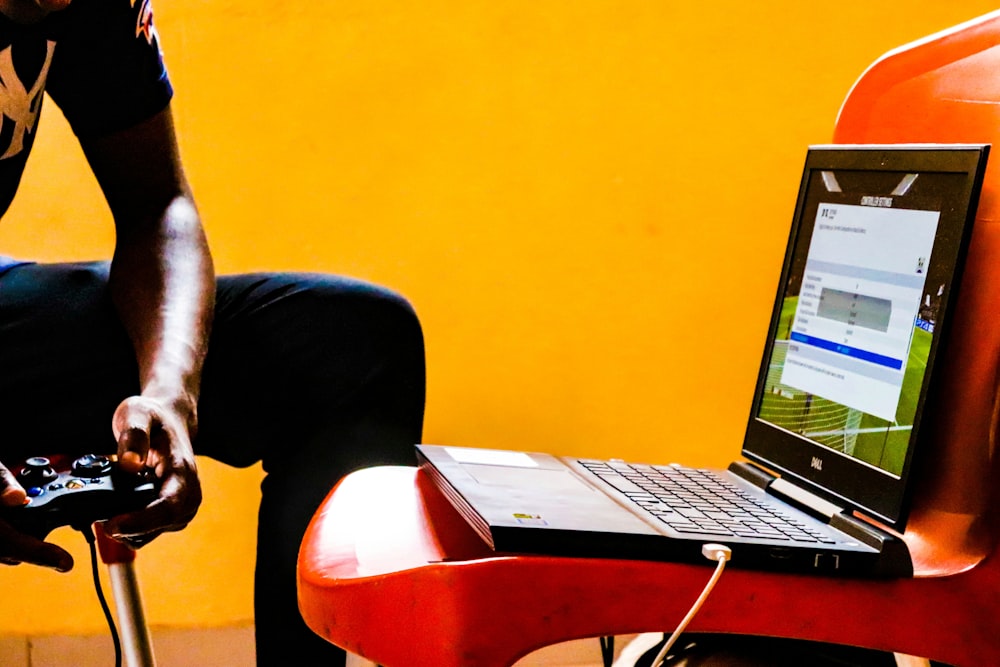 um homem sentado em uma cadeira com um laptop em seu colo