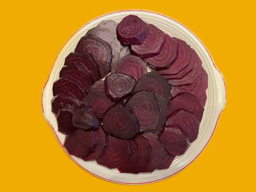 Deep-red beetroot slices arranged in an elegant pattern on a slate surface, showcasing their rich color and natural texture.