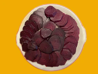 Deep-red beetroot slices arranged in an elegant pattern on a slate surface, showcasing their rich color and natural texture.