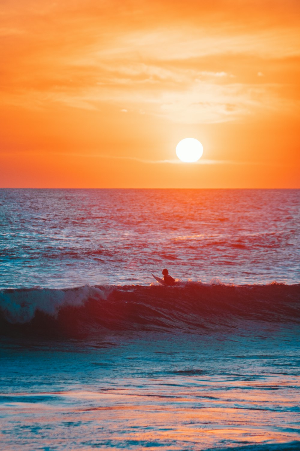 a person riding a surfboard on a wave at sunset