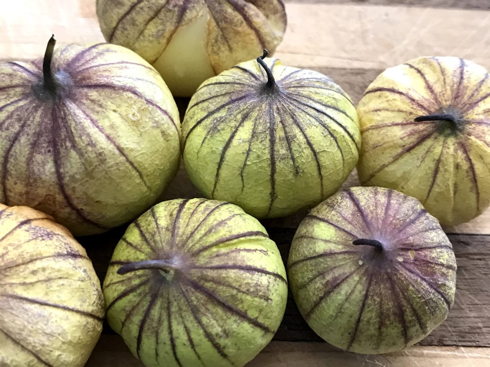 a pile of green apples sitting on top of a wooden table