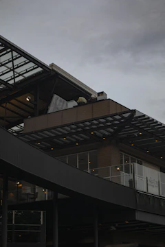 Facade of a sleek commercial building with glass and metal details under a moody sky.