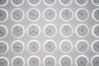 A colorful array of different clocks displayed on a bright wall in a trendy office.