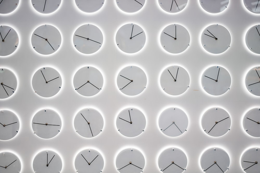 un mur blanc avec de nombreuses horloges