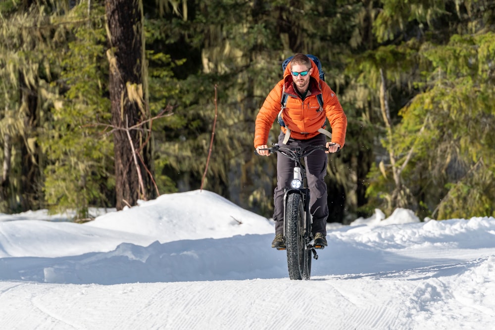 a man riding a bike down a snow covered road