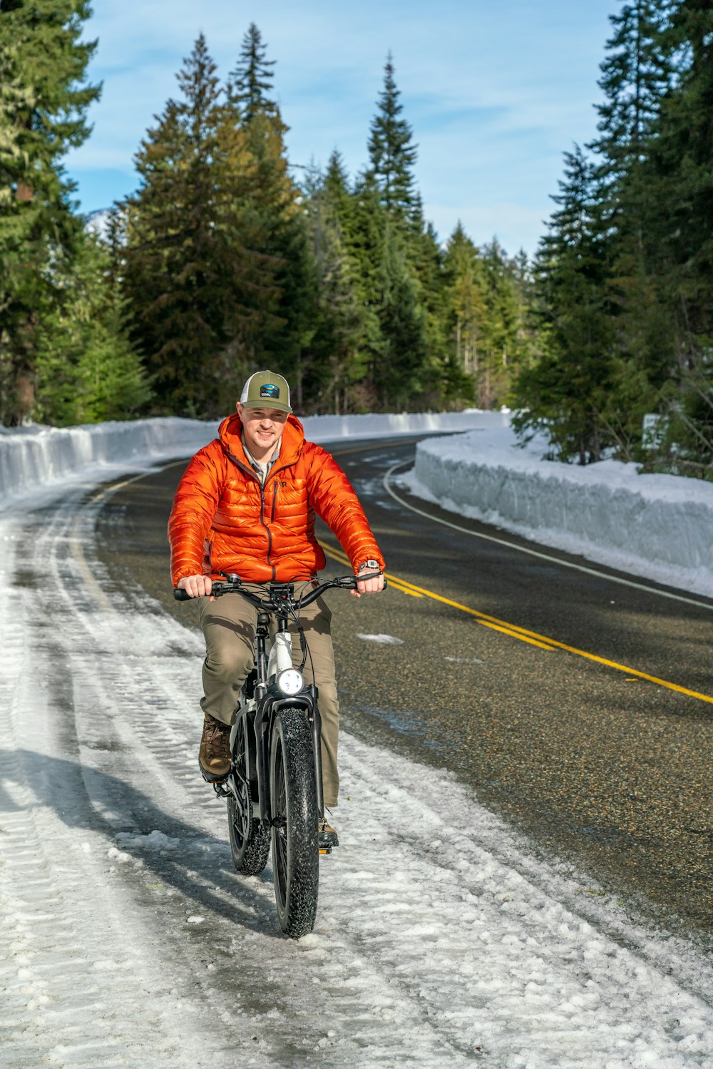 a man riding a bike down a snow covered road