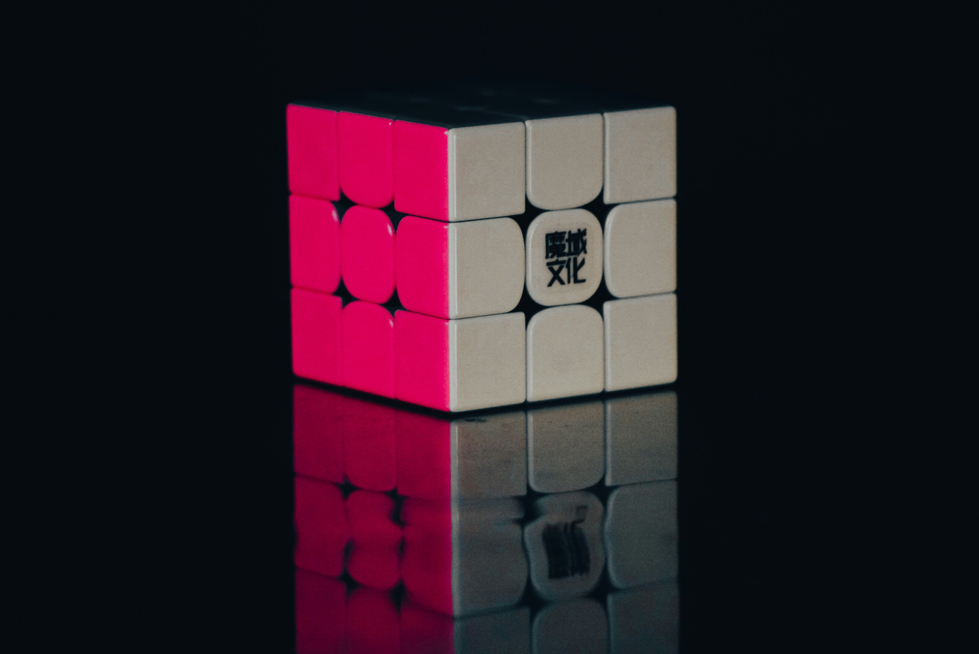 Un cubo rosa y blanco sentado encima de una superficie reflectante