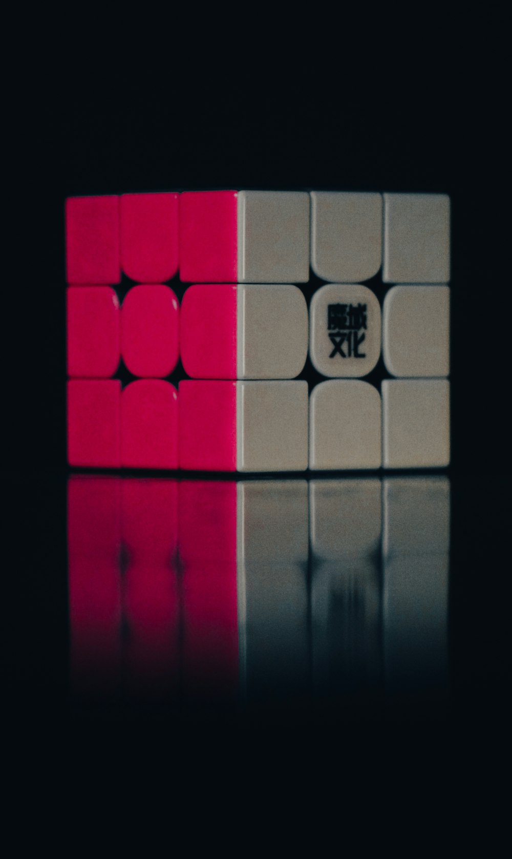 a pink and white cube sitting on top of a reflective surface