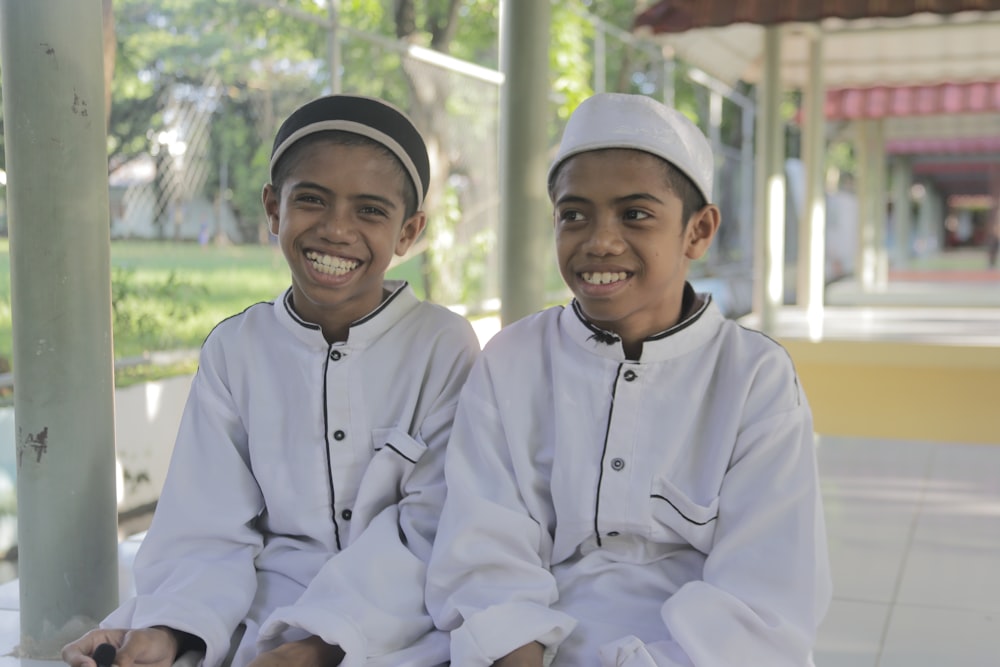 two young boys are sitting on a bench