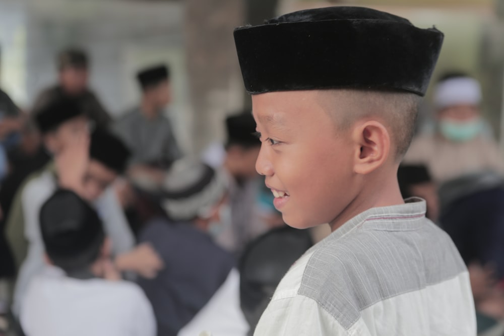 a young boy wearing a black hat in front of a group of people