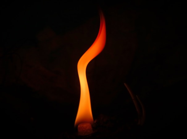 A vibrant violet flame symbol glowing softly against a dark background.