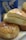 Golden, flaky biscuits drizzled with honey sit on a light wooden surface, with a can of biscuit dough visible in the background.