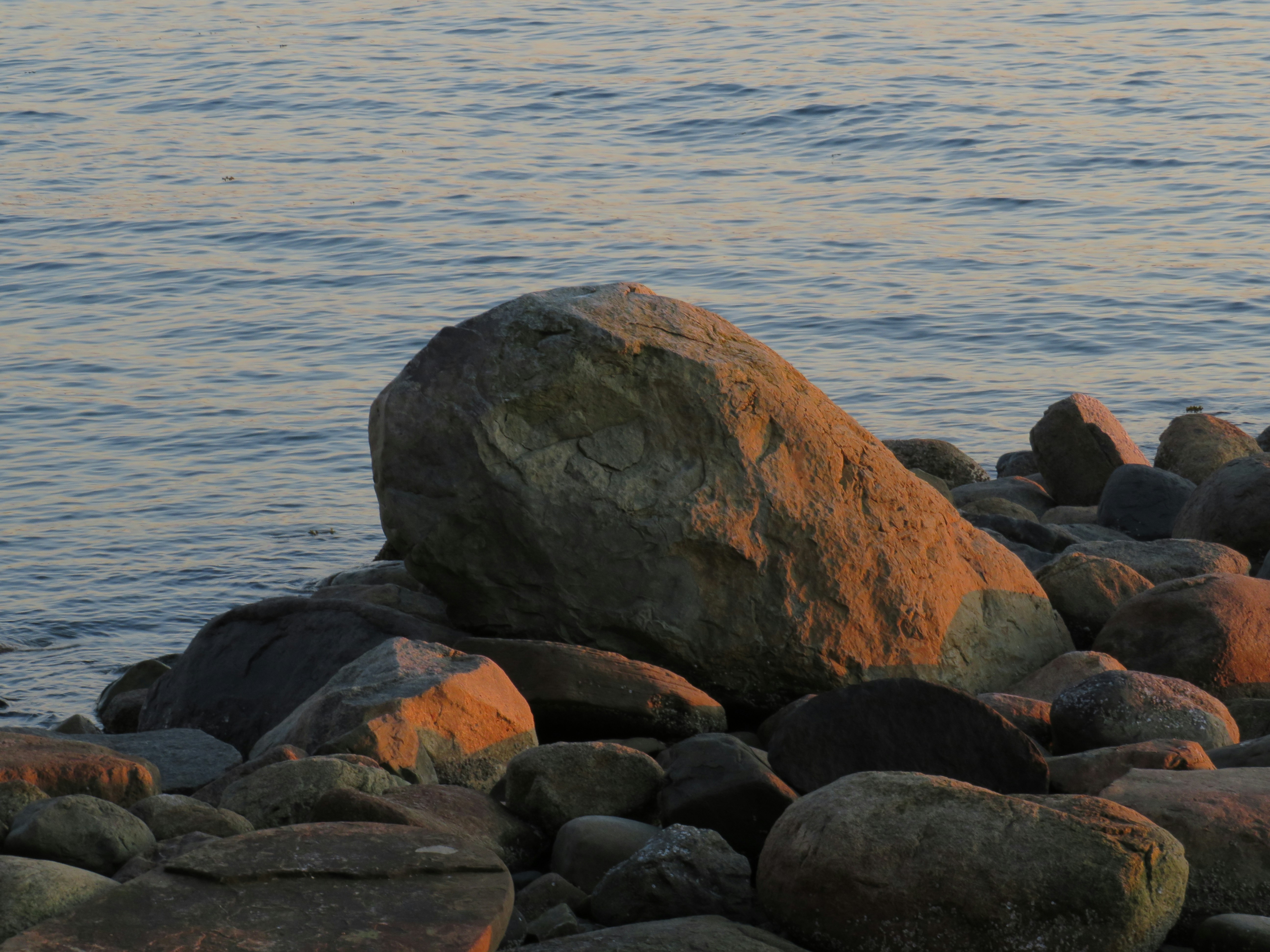 Ein großer Felsen auf einem Strand neben dem Meer