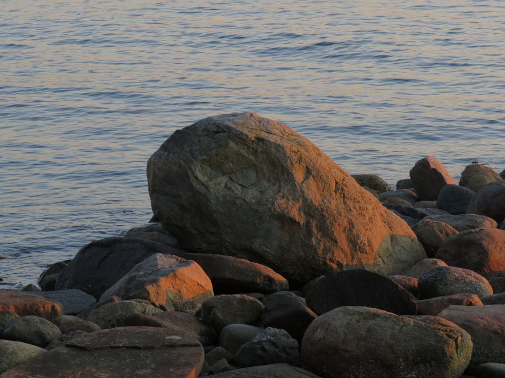 a large rock sitting on top of a beach next to the ocean