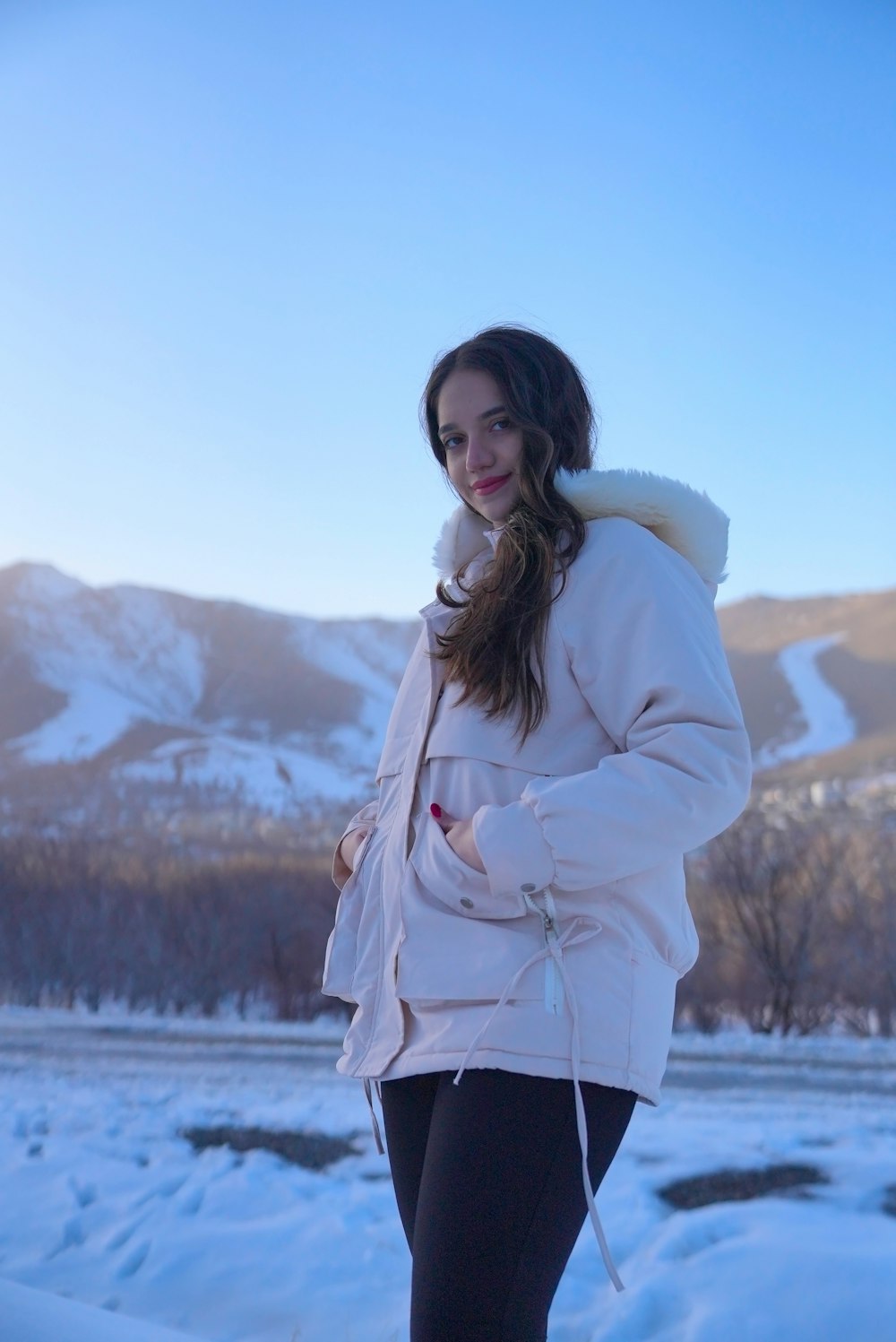 a woman standing in the snow wearing a jacket