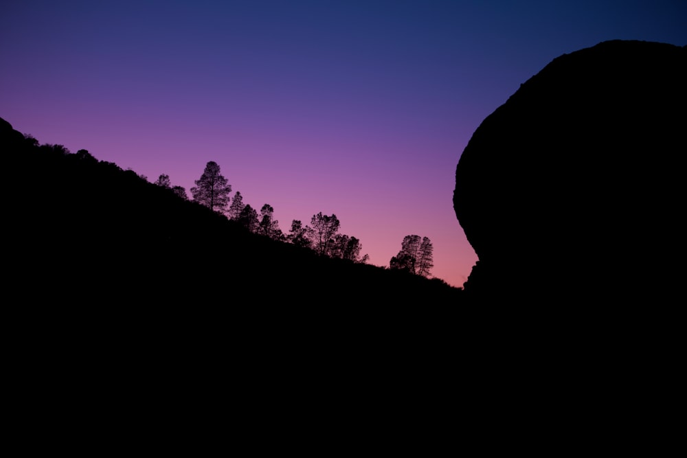 the silhouette of a mountain with trees in the background