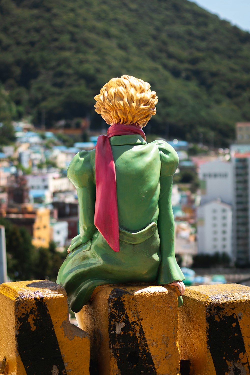 a statue of a woman sitting on top of a yellow fence