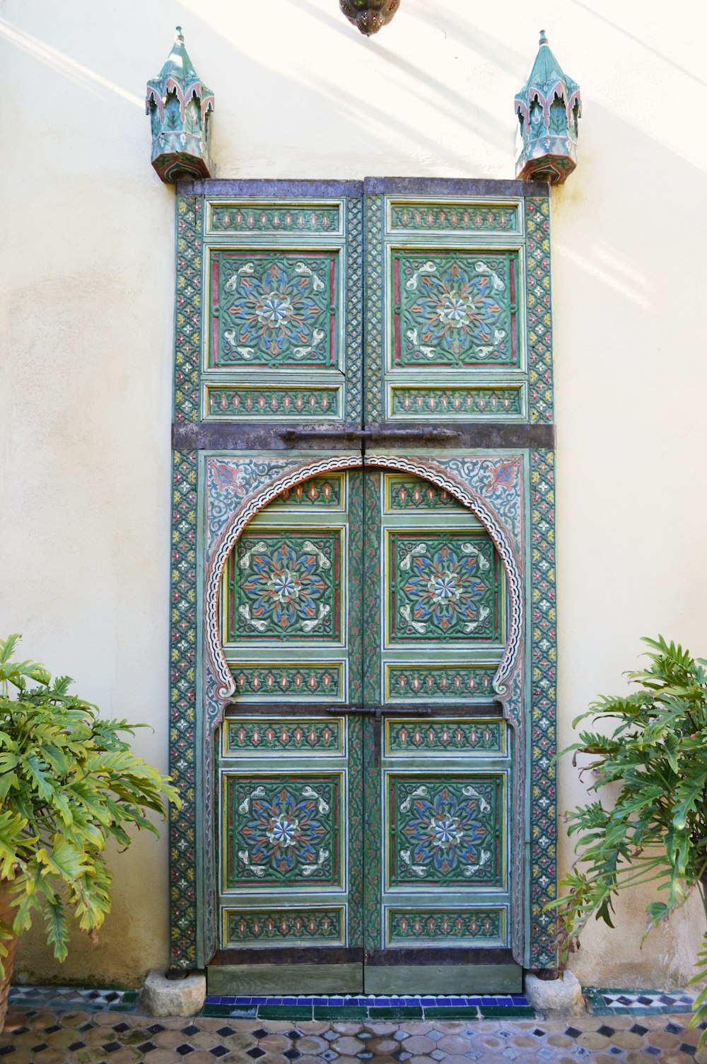a green door with ornate designs on the side of a building