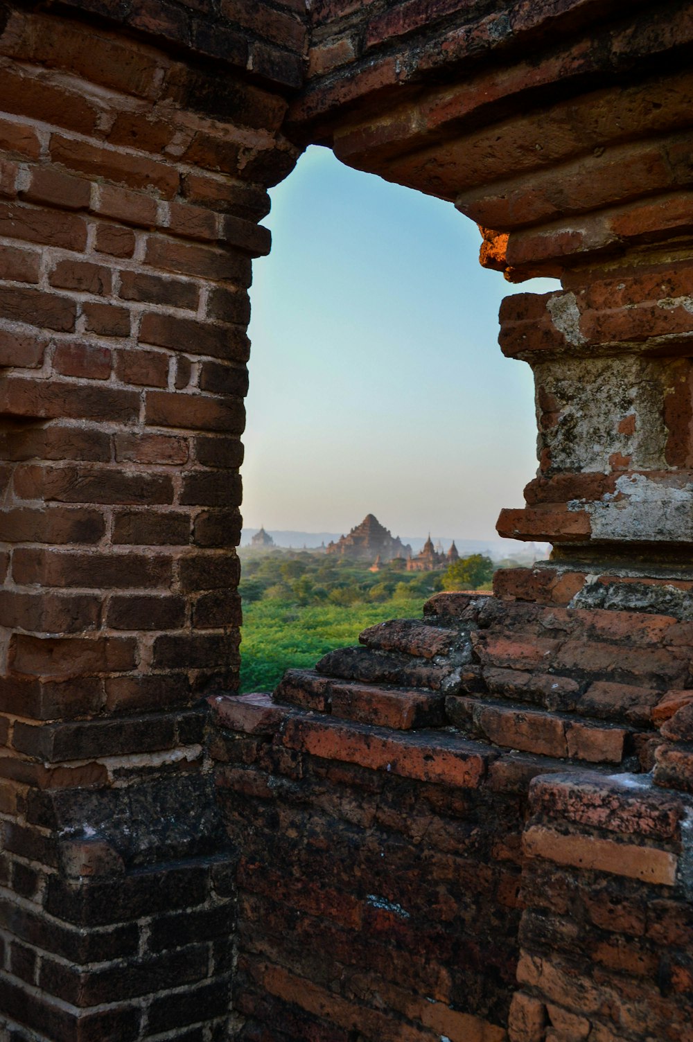 a window in a brick wall with a view of a valley