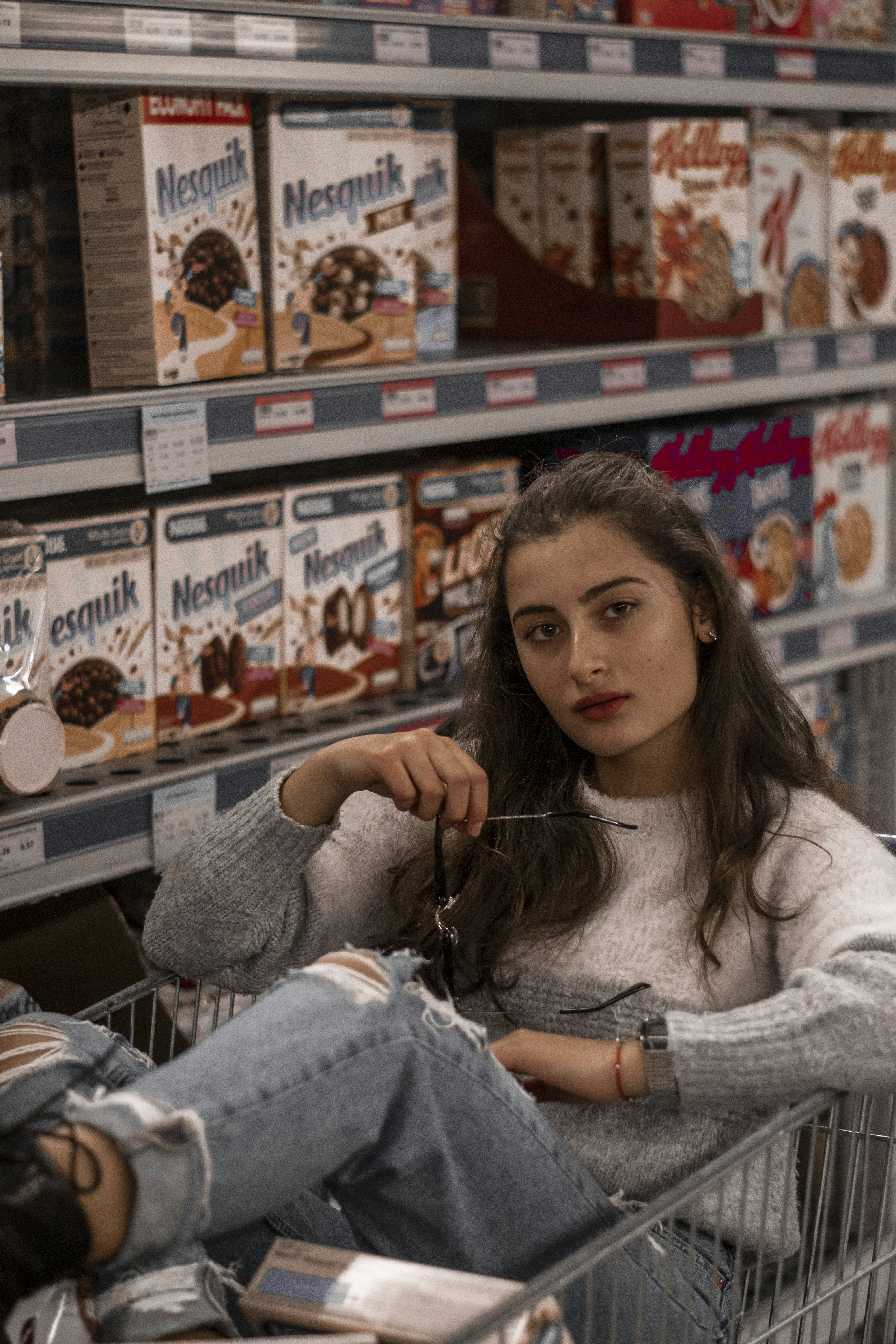uma mulher sentada em um carrinho de compras em uma loja