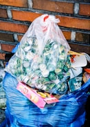 a bag full of garbage sitting next to a brick wall