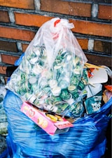a bag full of garbage sitting next to a brick wall