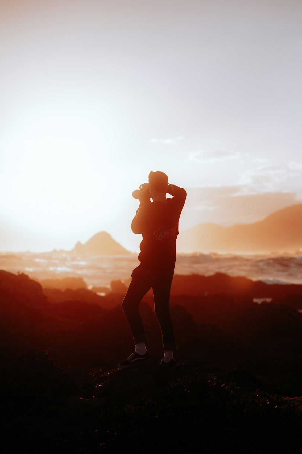 a man standing on top of a hill next to the ocean