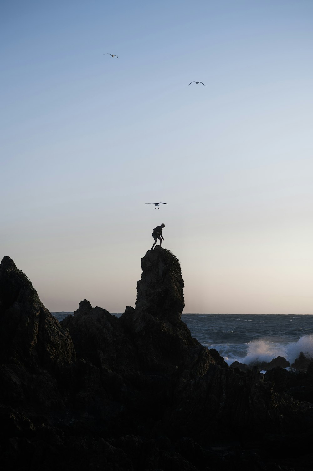 a person standing on top of a rock near the ocean