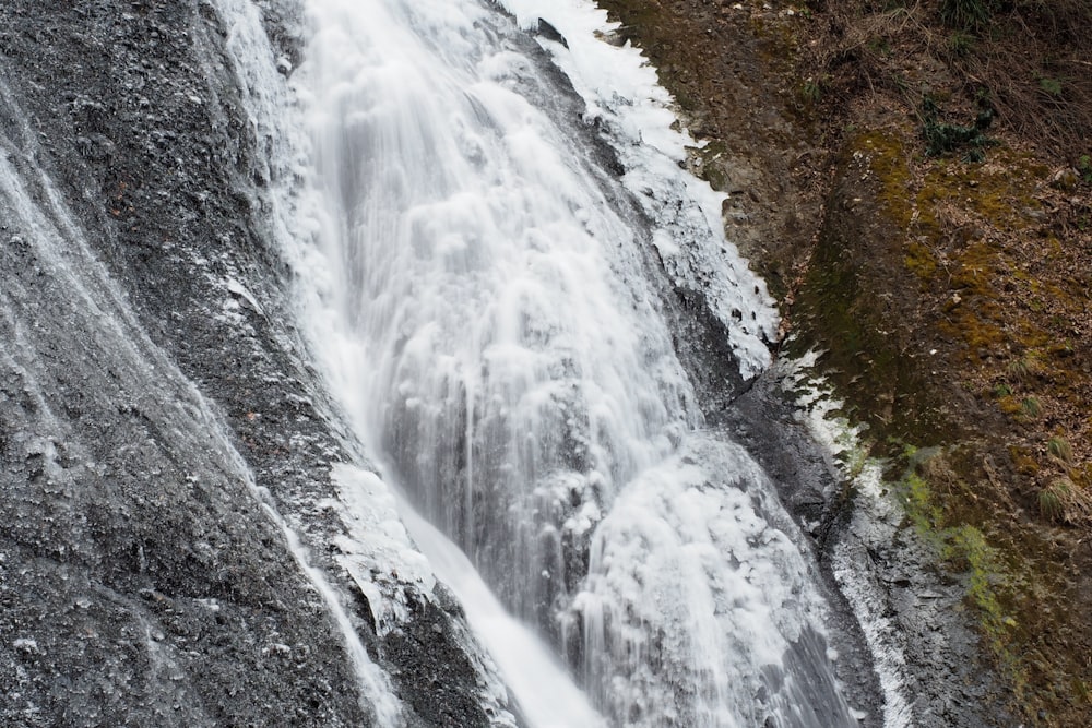 Ein Mann steht an der Seite eines Wasserfalls