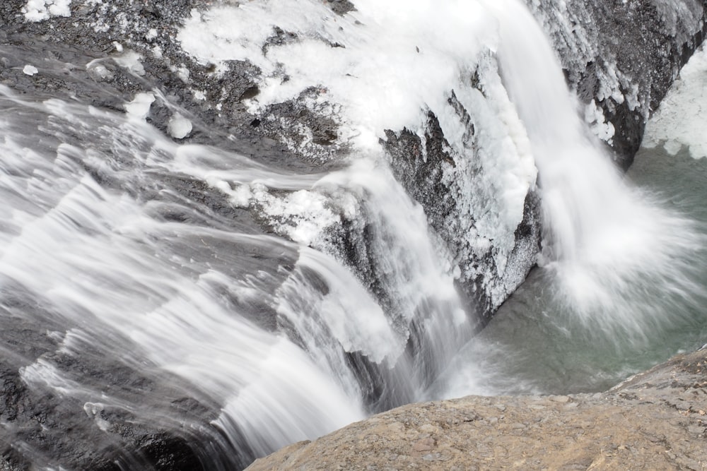 a man standing on a rock next to a waterfall