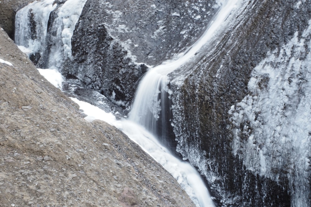 a man standing on top of a rock next to a waterfall