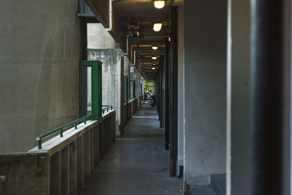 a long hallway between two buildings with green railings