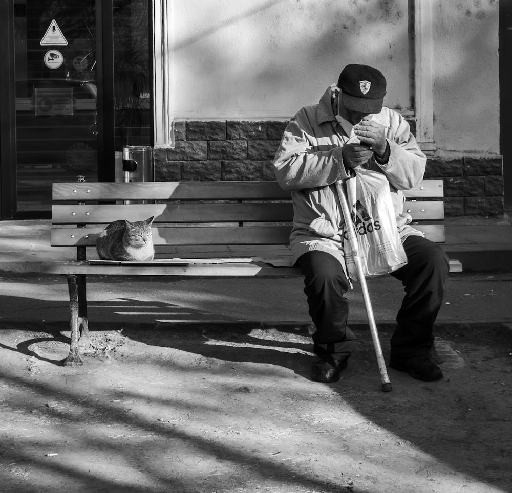 a man sitting on a bench next to a cat