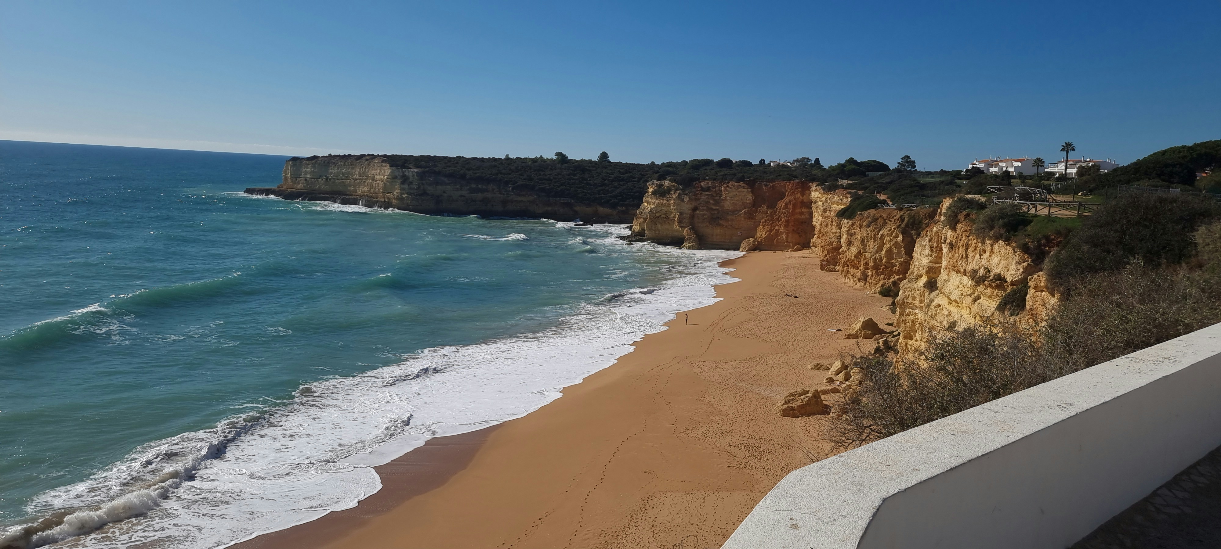 a sandy beach next to the ocean with a cliff in the background