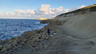 a person standing on a rocky beach next to the ocean