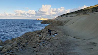 a person standing on a rocky beach next to the ocean