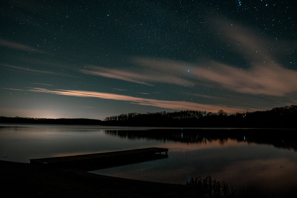 the night sky is reflected in the still water of a lake