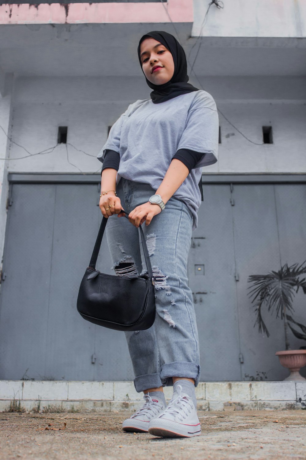 a woman in a hijab holding a black purse