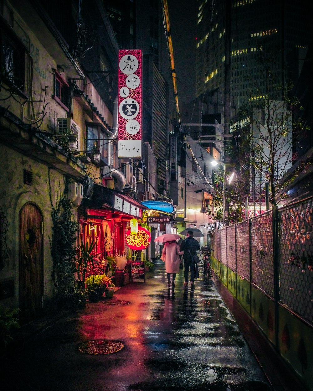 a couple of people walking down a rain soaked street