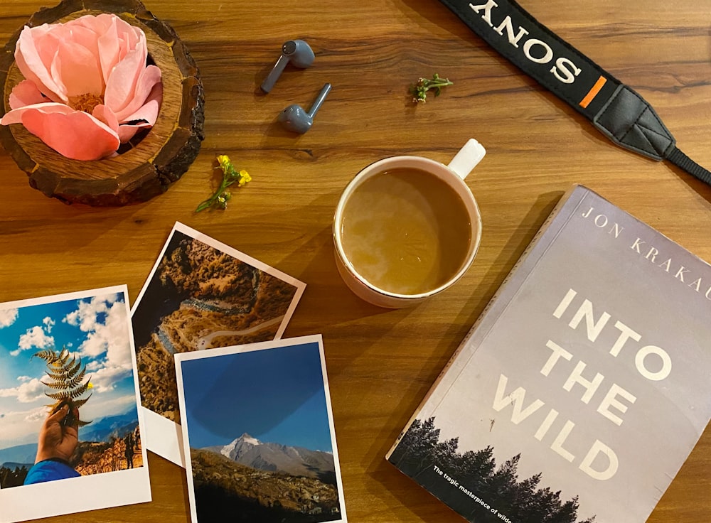 a wooden table topped with pictures and a cup of coffee