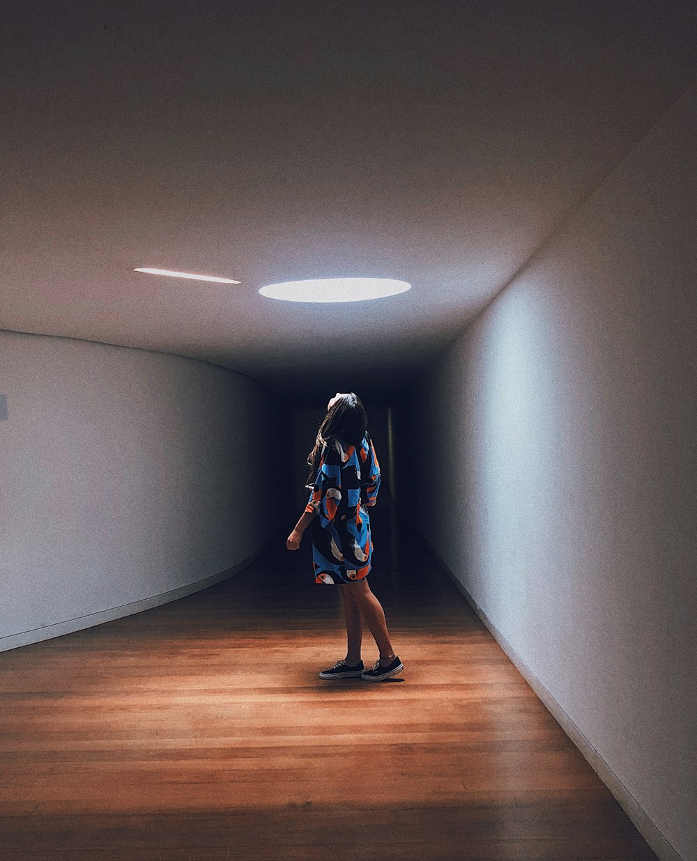 a woman is walking down a dark hallway