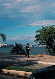 a man walking down a street next to a body of water
