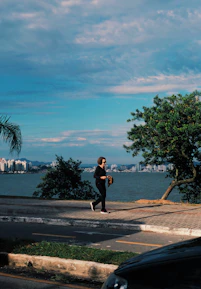 a man walking down a street next to a body of water