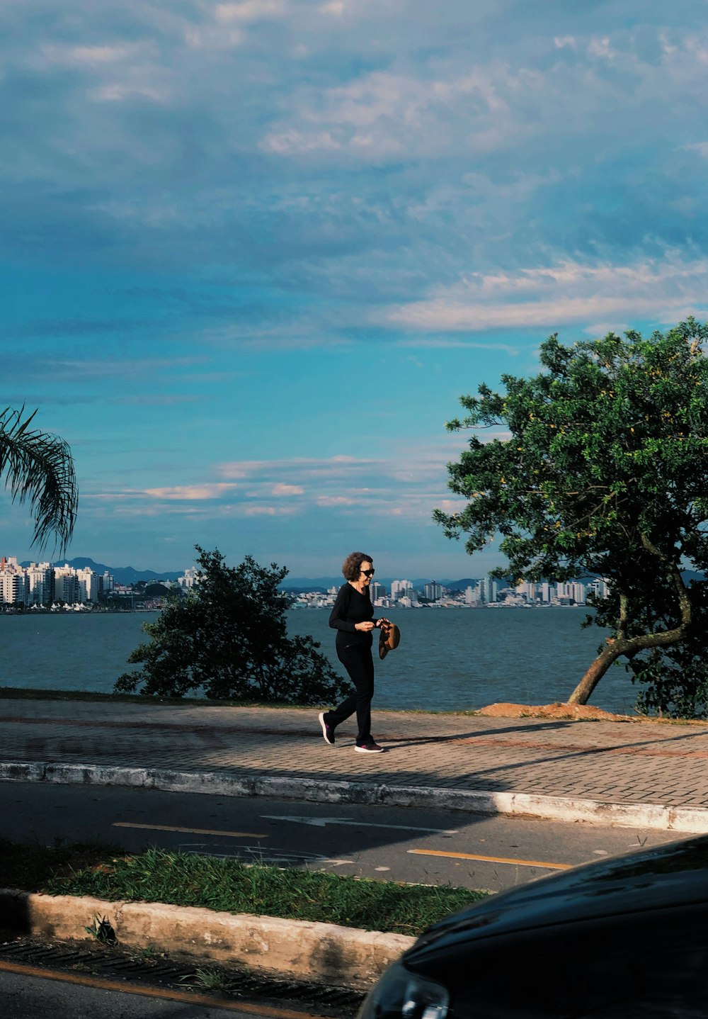 a man walking down a street next to a body of water