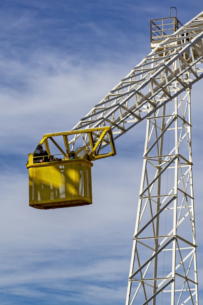 a yellow lift is attached to a tall tower