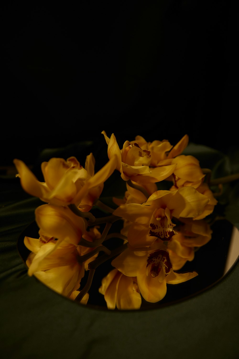 a black plate topped with yellow flowers on top of a table